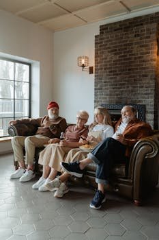 Elderly friends enjoying a relaxing time together in a cozy indoor setting by the fireplace.